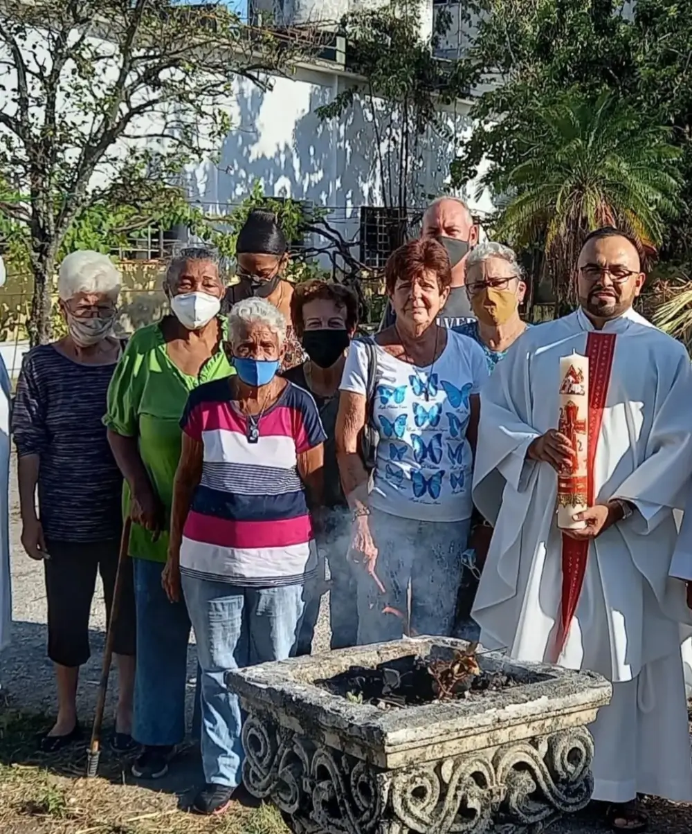 A group of people posing with a priest holding a candle